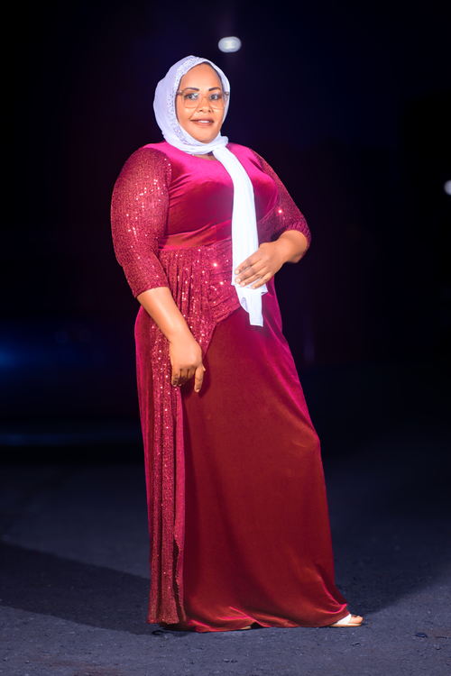Free Stylish woman in a red dress and hijab posing confidently at night. Stock Photo