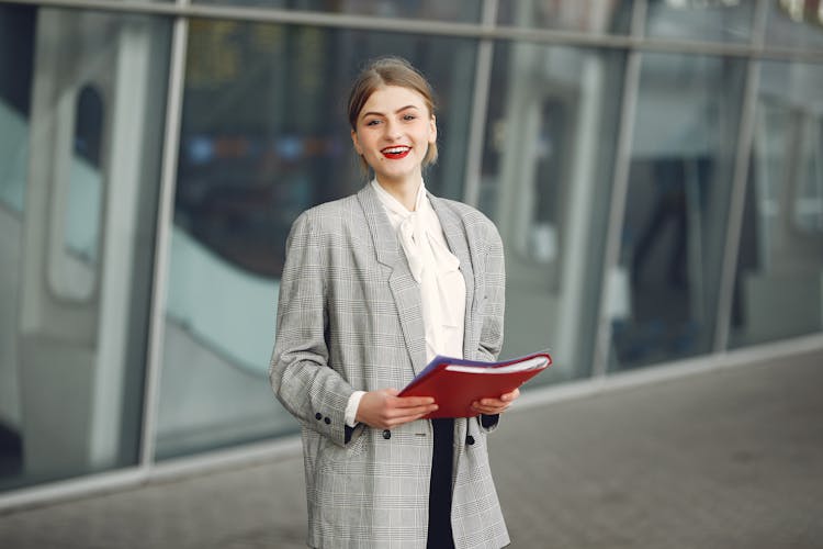 Happy Female Manager With Papers Near Office Building