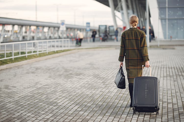 Unrecognizable Woman With Suitcase Walking Near Airport Terminal