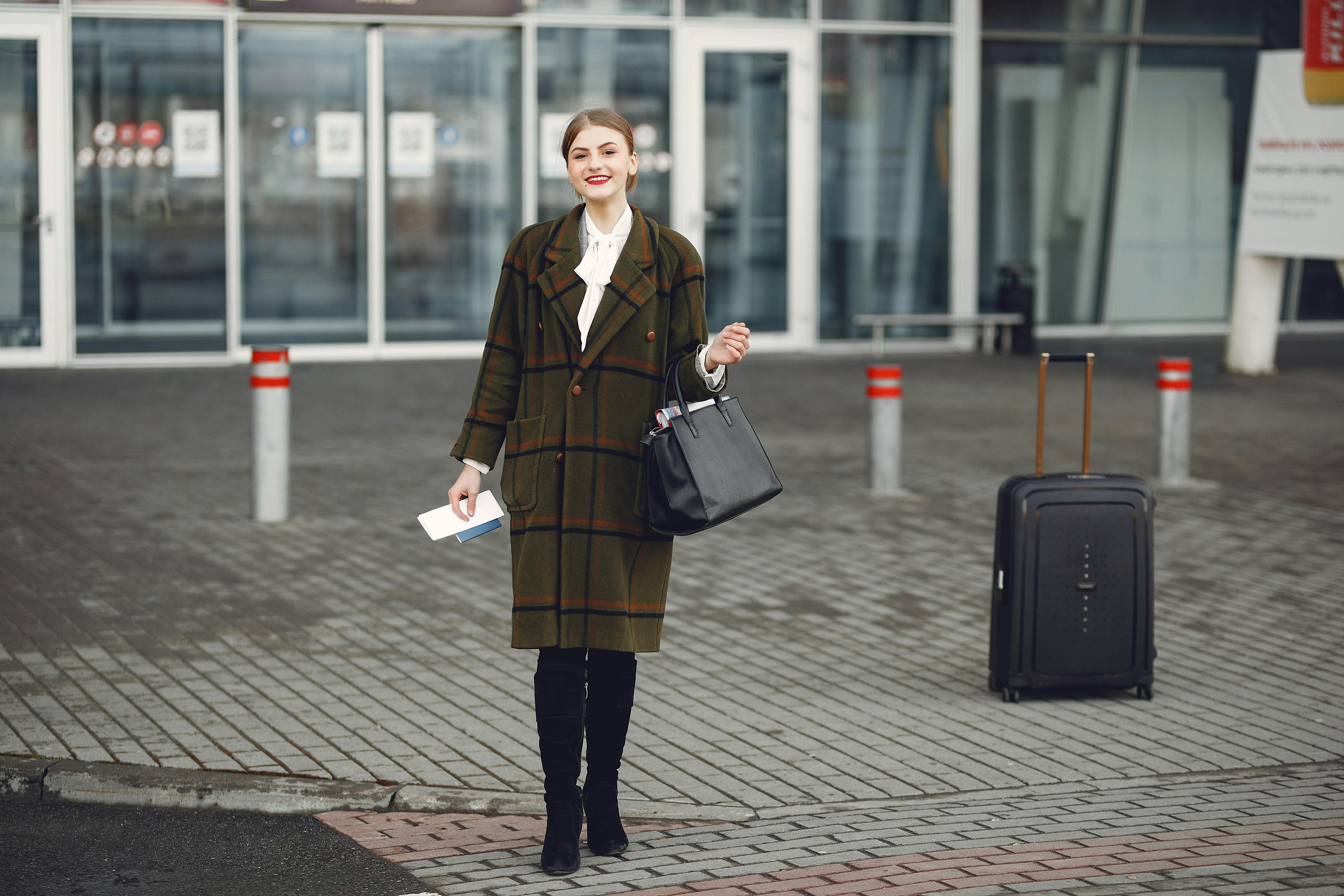 Fashionable woman with luggage arrives at airport ready for travel.