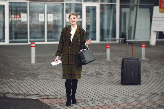 Stylish woman traveling with luggage and handbag