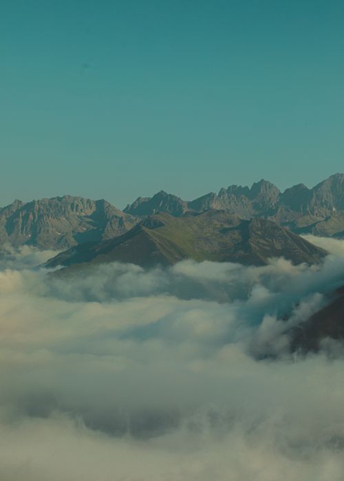 Free Breathtaking view of mountains rising above a sea of clouds under a clear sky. Stock Photo