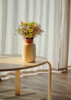 A vibrant bouquet of spring flowers in a ceramic vase on a minimalist table with natural light.