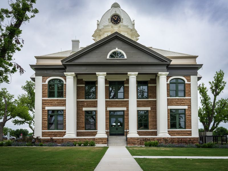 Classic courthouse building framed by lush green trees