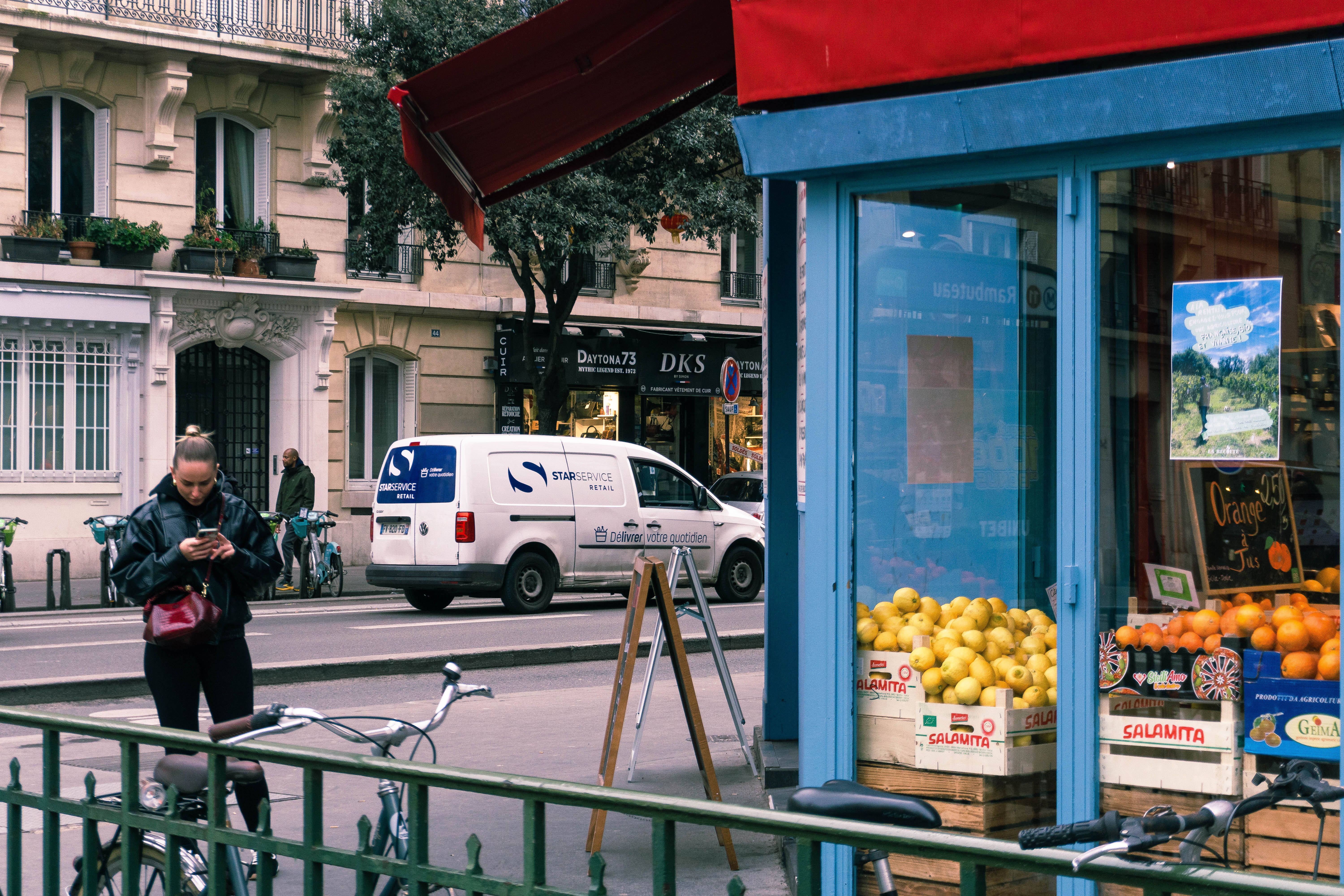 A vibrant street scene in Paris featuring a market shop with fresh produce and pedestrians.