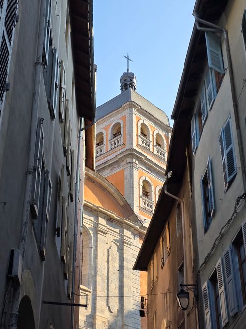 Free A historic European church tower view framed by narrow cobblestone streets under clear blue skies. Stock Photo