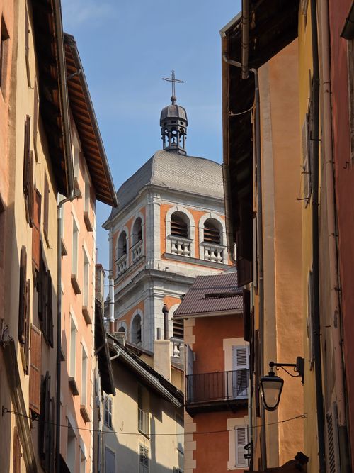 Free Charming view of a European alleyway with a historic bell tower under clear skies. Stock Photo