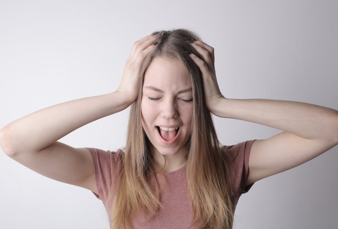 Young frustrated woman screaming with closed eyes