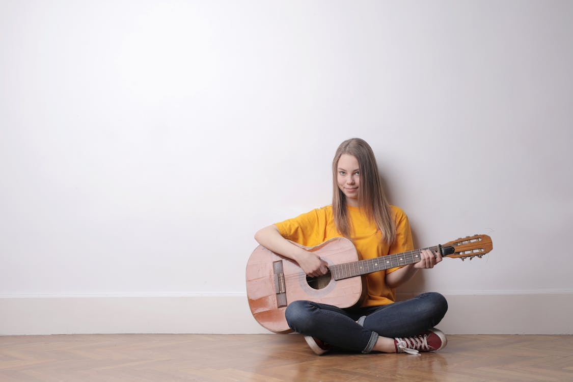Woman in Yellow Crew-neck T-shirt and Black Pants Playing  Acoustic Guitar