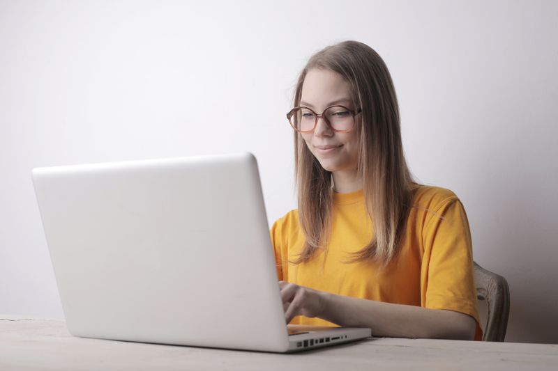 Woman in glasses working intently at a laptop, concentrating on her screen