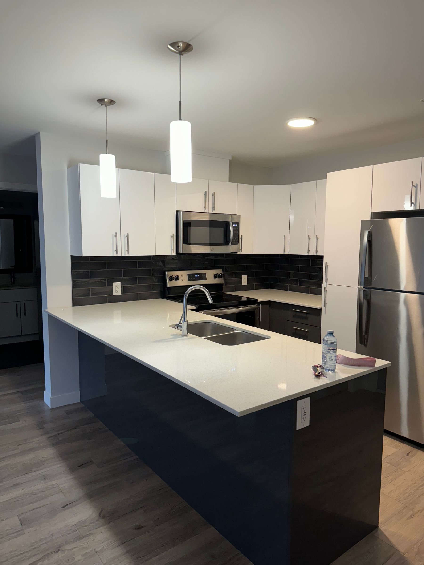 Modern minimalist kitchen with a darker backsplash, light cabinetry and functional counter lighting