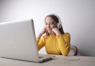 Woman In Yellow Sweater Sitting On Chair In Front Of A Laptop