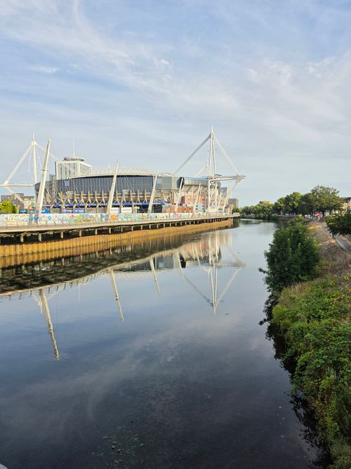 Free Scenic view of stadium reflecting in calm river under a sunny sky. Stock Photo