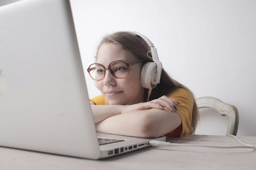 Free Woman Using White Headphones Using Macbook Stock Photo