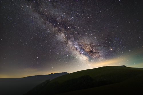 Free Breathtaking view of the Milky Way galaxy over dark hills, illuminating the night sky. Stock Photo