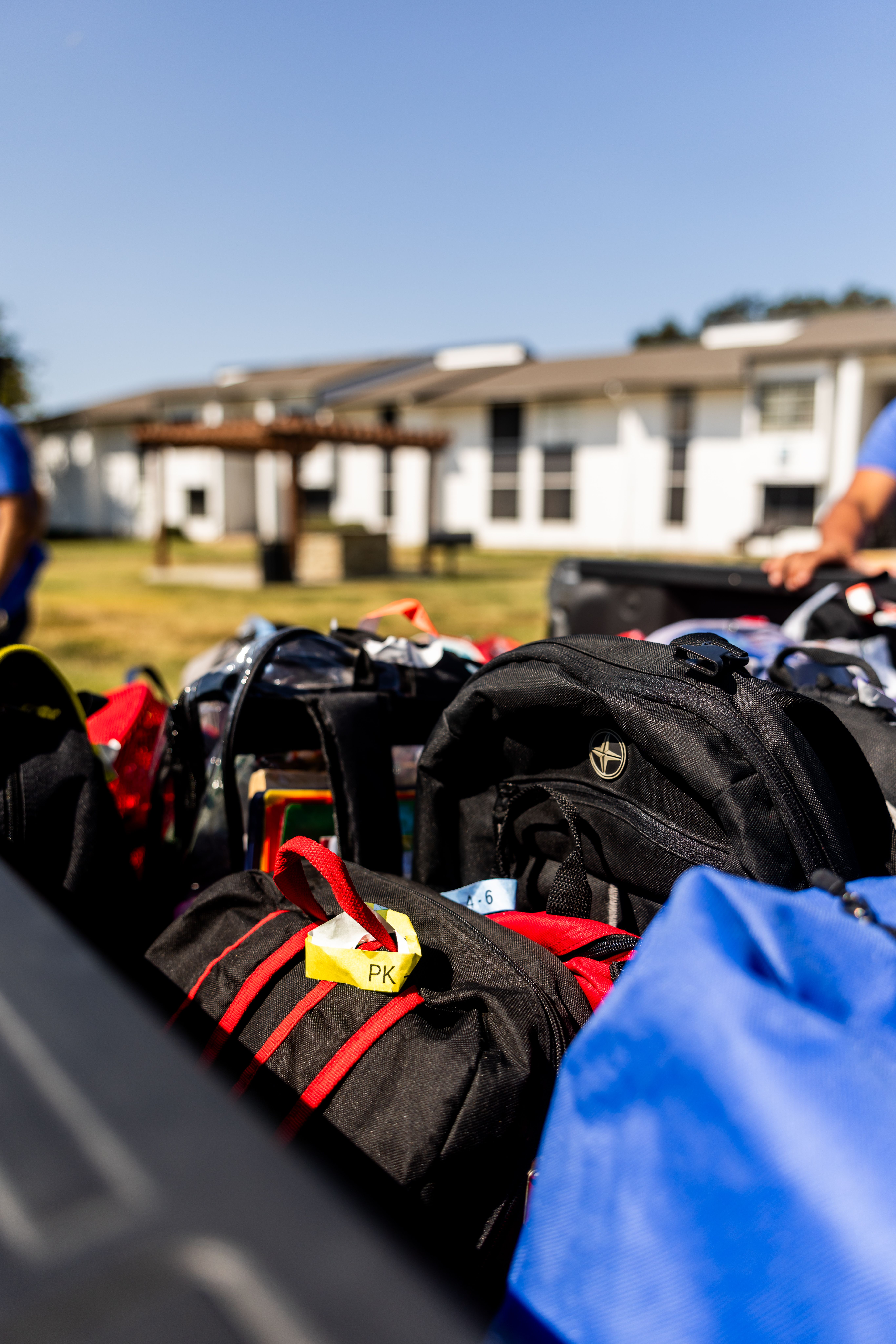 A collection of colorful backpacks ready for a school or camping trip under a clear blue sky.