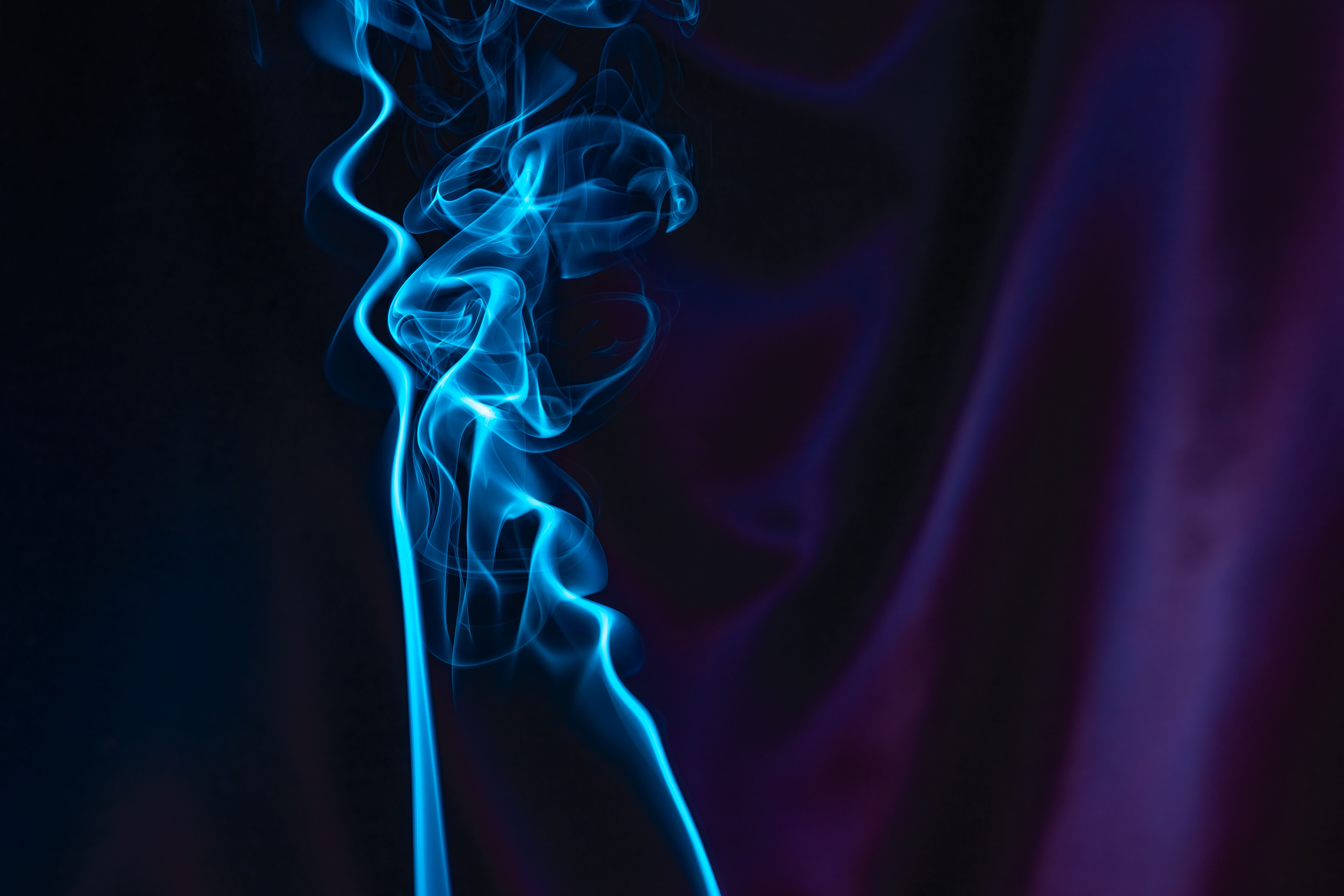 Fotomural Intrincados patrones de humo azul que se elevan contra un fondo oscuro y misterioso.