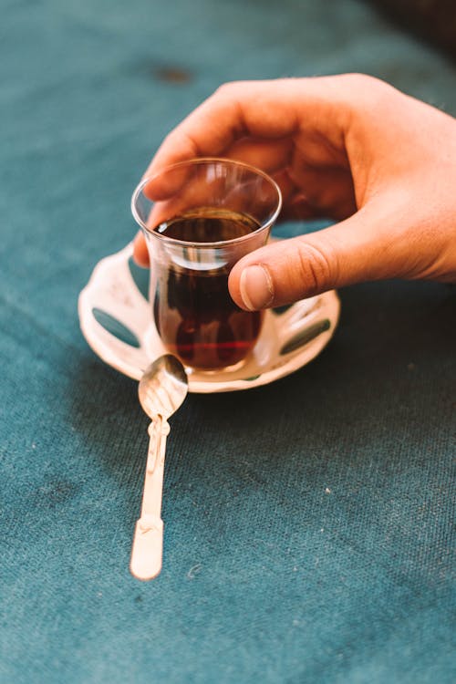 Free From above of crop anonymous person drinking hot tea from traditional Arabic glass placed on saucer Stock Photo