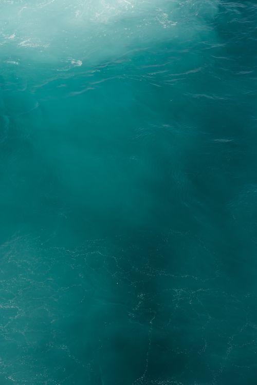 Free A vibrant teal ocean surface showcasing natural water textures and reflections. Stock Photo