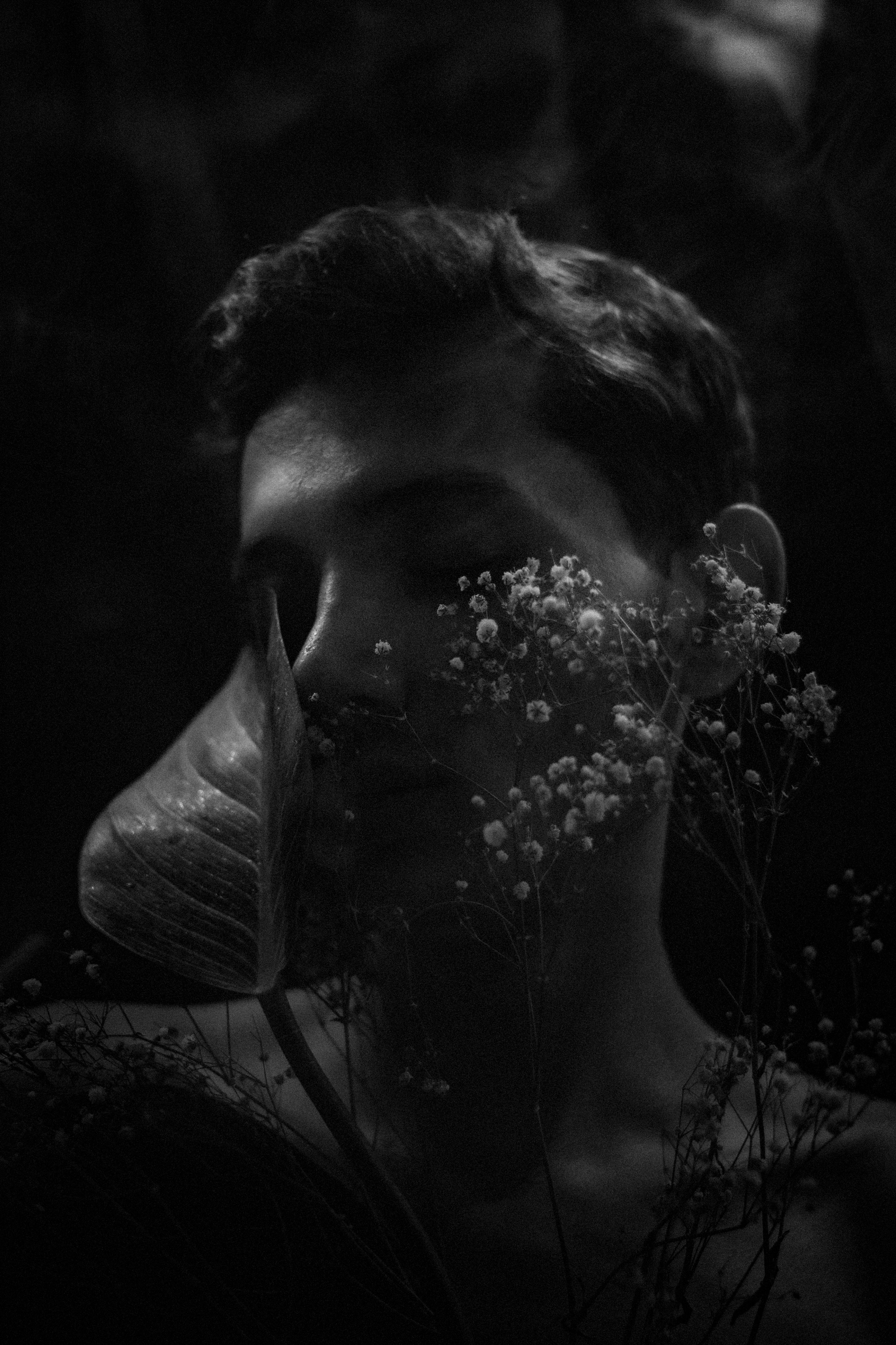 A moody black and white portrait with floral elements and soft lighting.