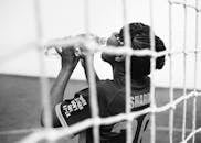 Black and white back view of young female goalkeeper drinking water from plastic bottle