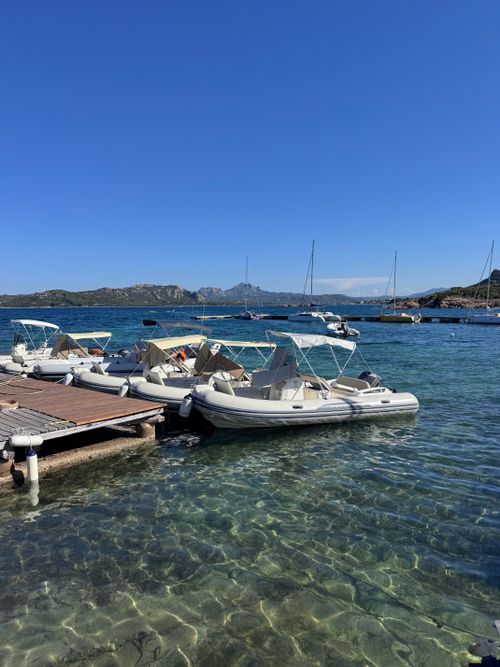 Free Clear waters at a boat dock in Sardinia, Italy with a stunning coastal landscape. Stock Photo