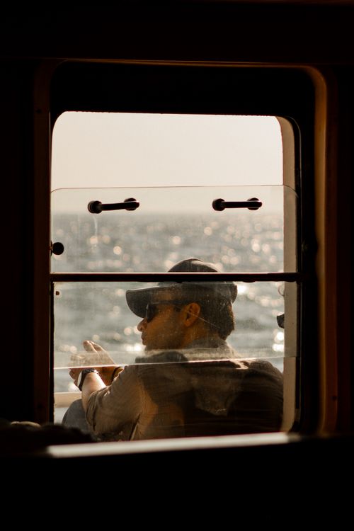 Free Man on a nautical voyage gazes through a window at the serene ocean scenery. Stock Photo