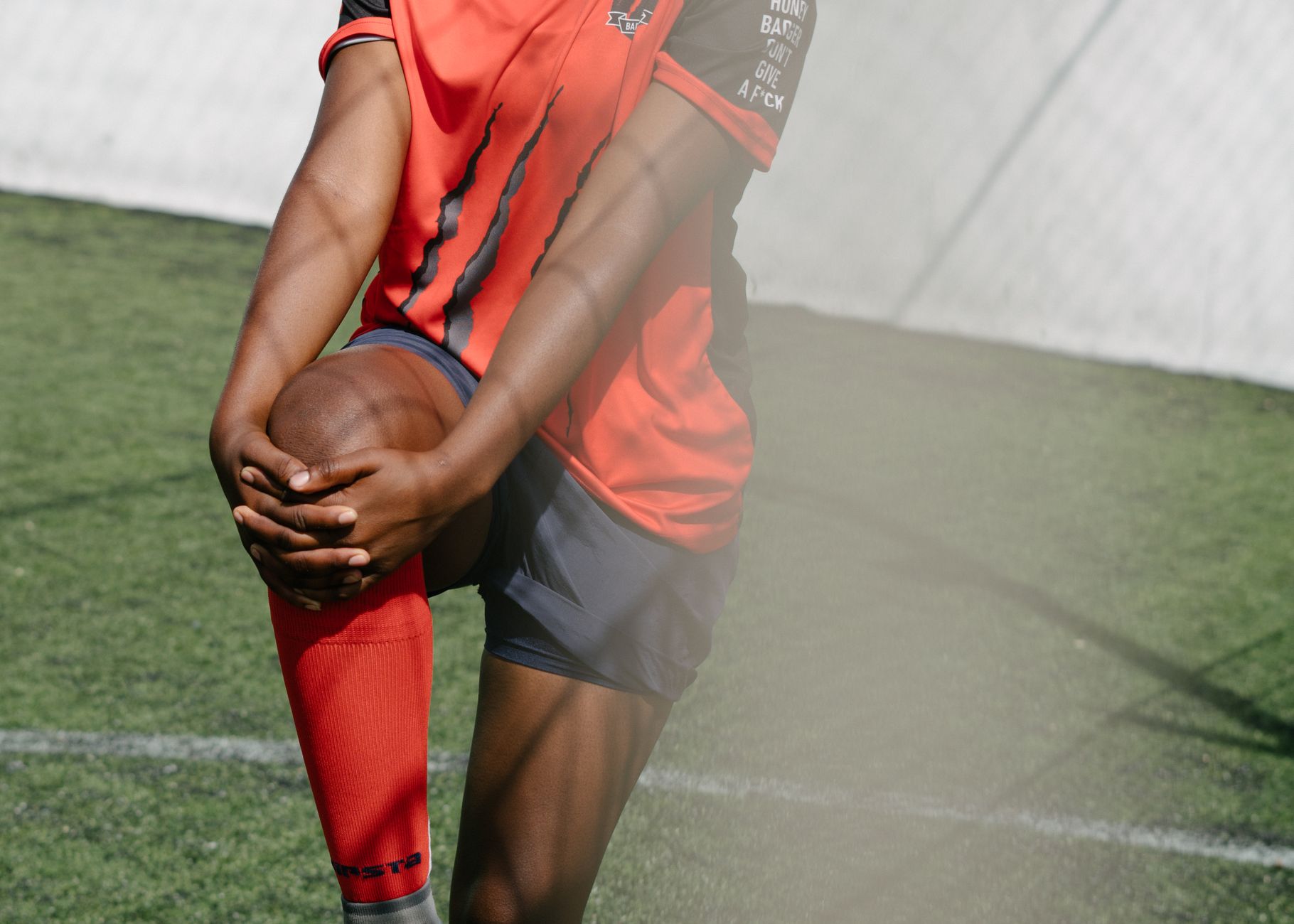 Crop faceless female African American football player stretching leg before coming on field