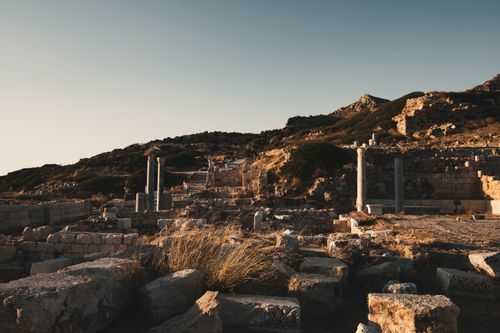 Free Explore ancient ruins set against a sunset landscape, featuring stone columns and rugged terrain. Stock Photo