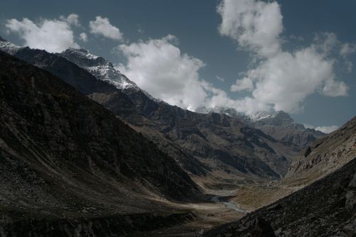 Free A serene mountain valley with dramatic snow-capped peaks under a cloudy sky. Stock Photo