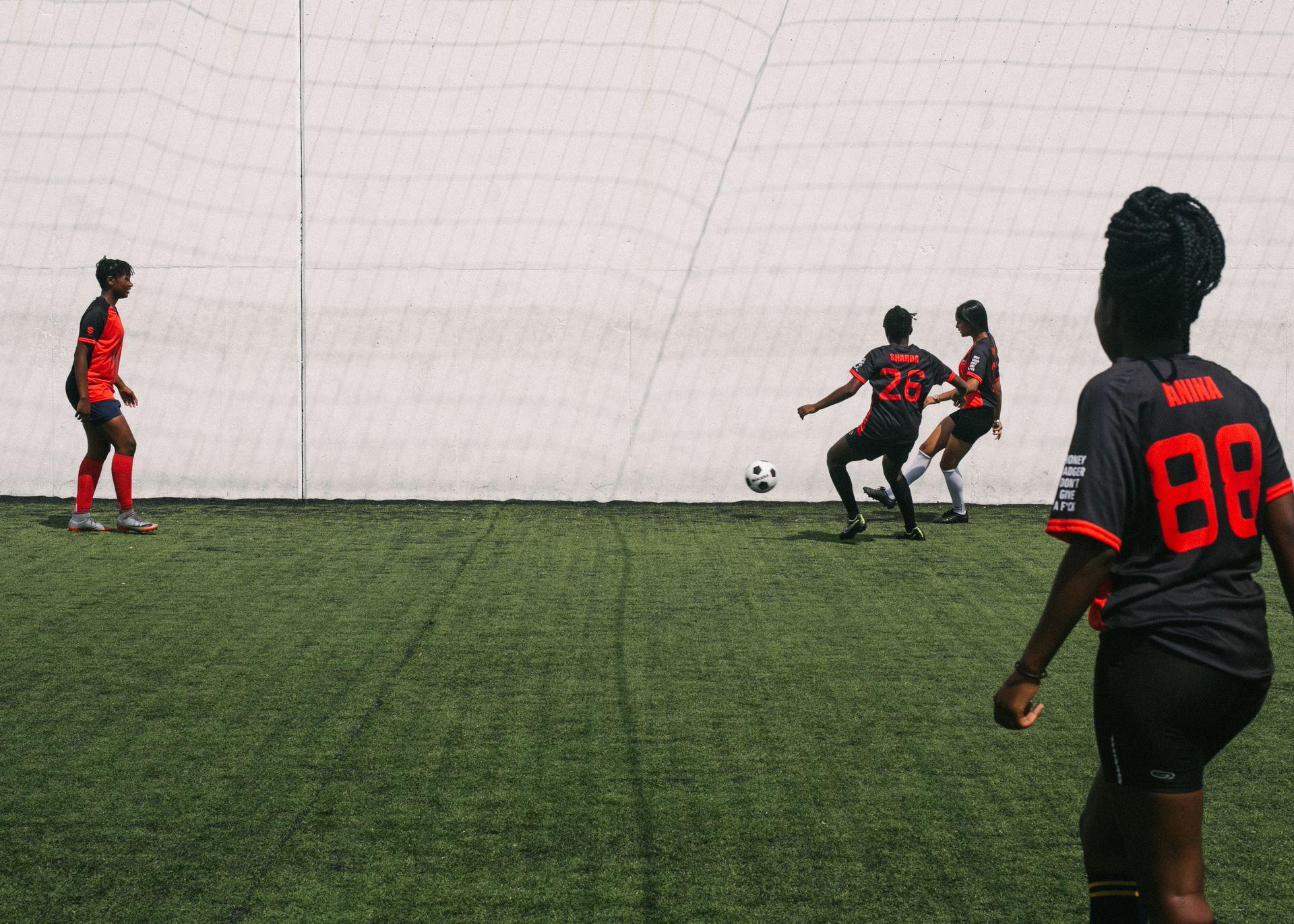 African American females actively playing in football on grass field of sports ground