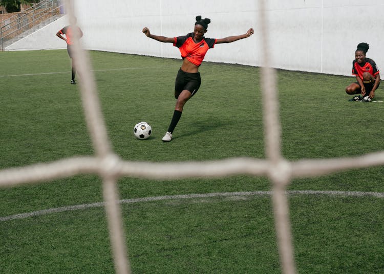 Girl In Red Shirt And Black Shorts Kicking A Soccer Ball