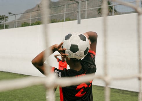 Teen player preparing a throw-in during a soccer match on an outdoor field.