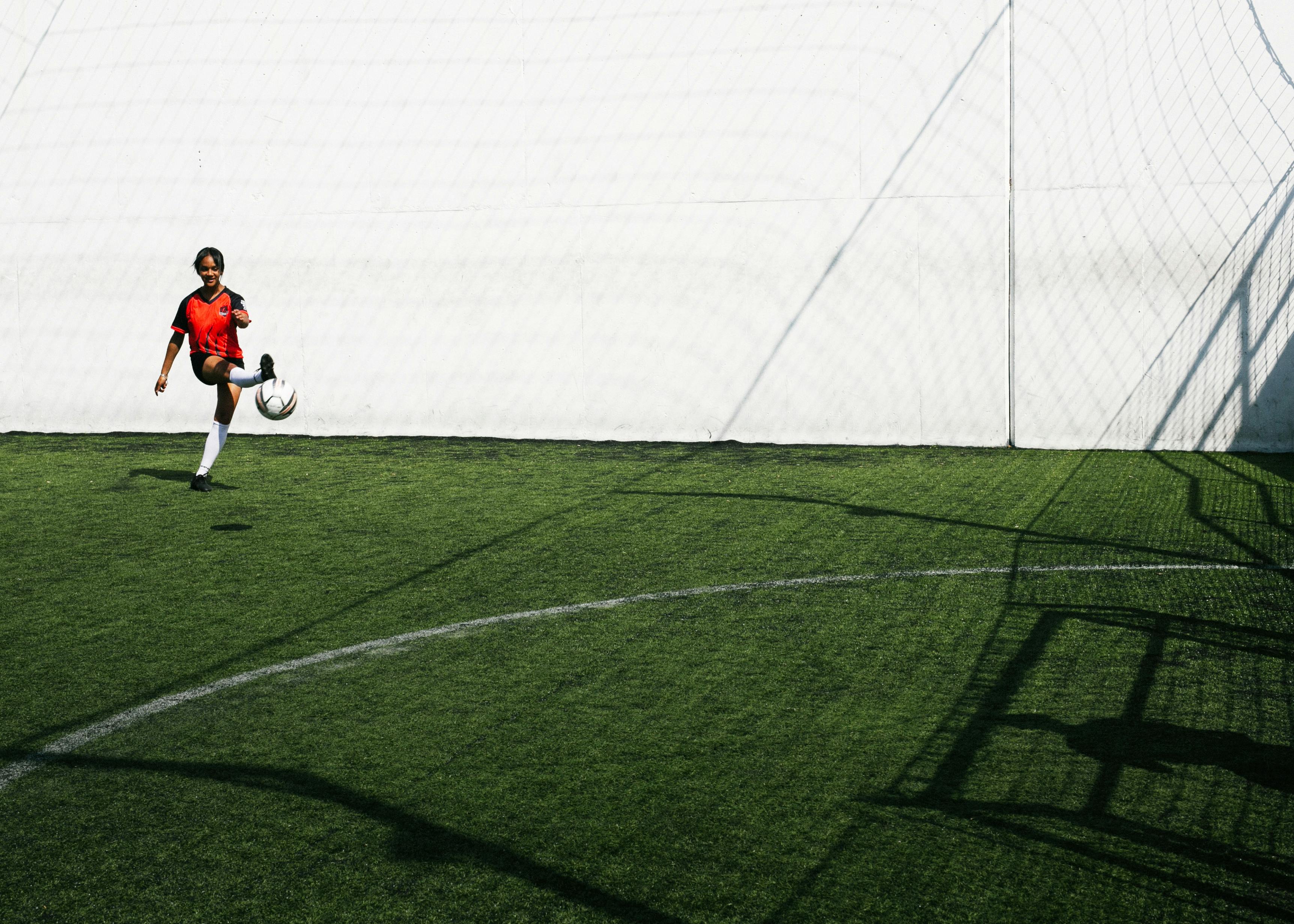 woman soccer player kicking ball in goal