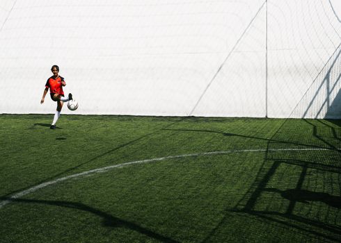 Young African American female football player trying scoring goal in training in sunny day