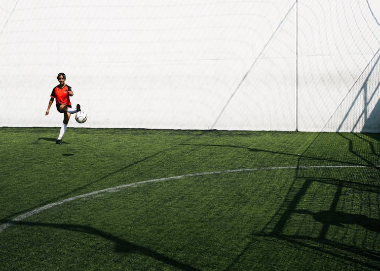 Woman Soccer Player Kicking Ball In Goal