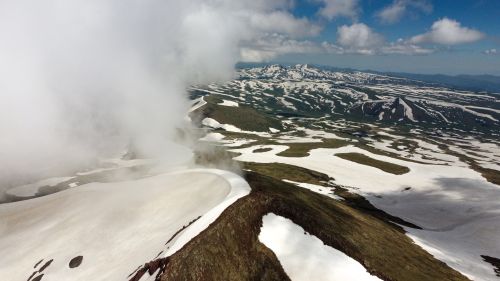 Free A stunning aerial panorama of snow-capped mountains in Kotayk Province, Armenia, with dramatic clouds and lush green valleys. Stock Photo
