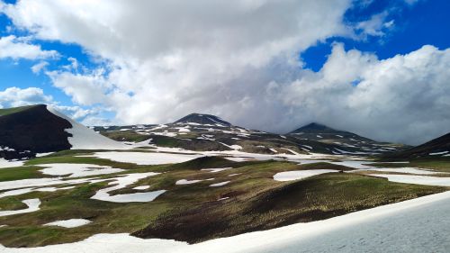Free Stunning panoramic view of snow-covered mountains in Kotayk Province, Armenia under dramatic clouds. Stock Photo