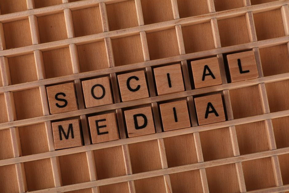 Wooden Scrabble tiles arranged to spell 'Social Media' on a grid background.