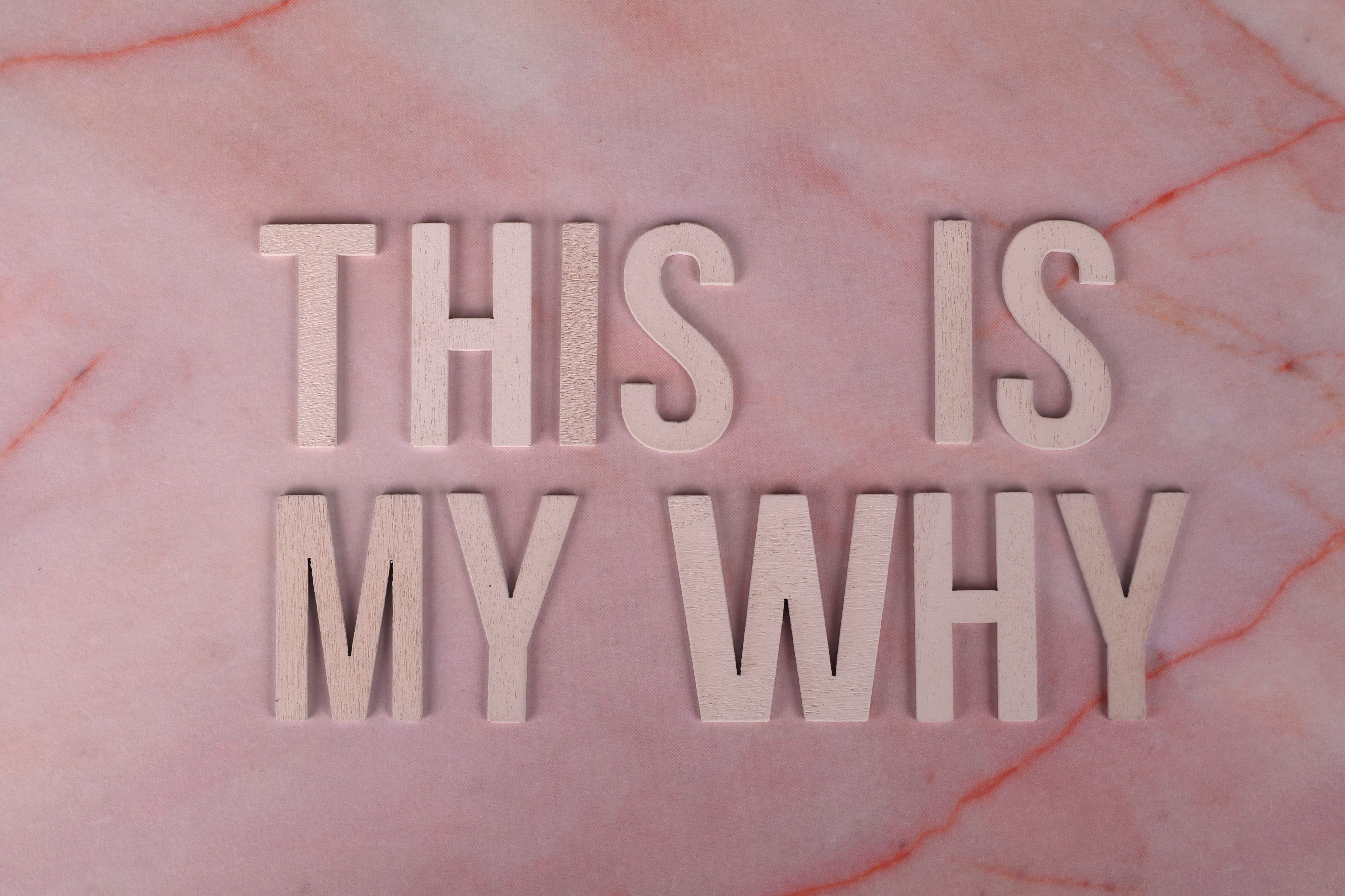 Wooden letters forming a motivational message on a pink marble backdrop, perfect for inspiration.