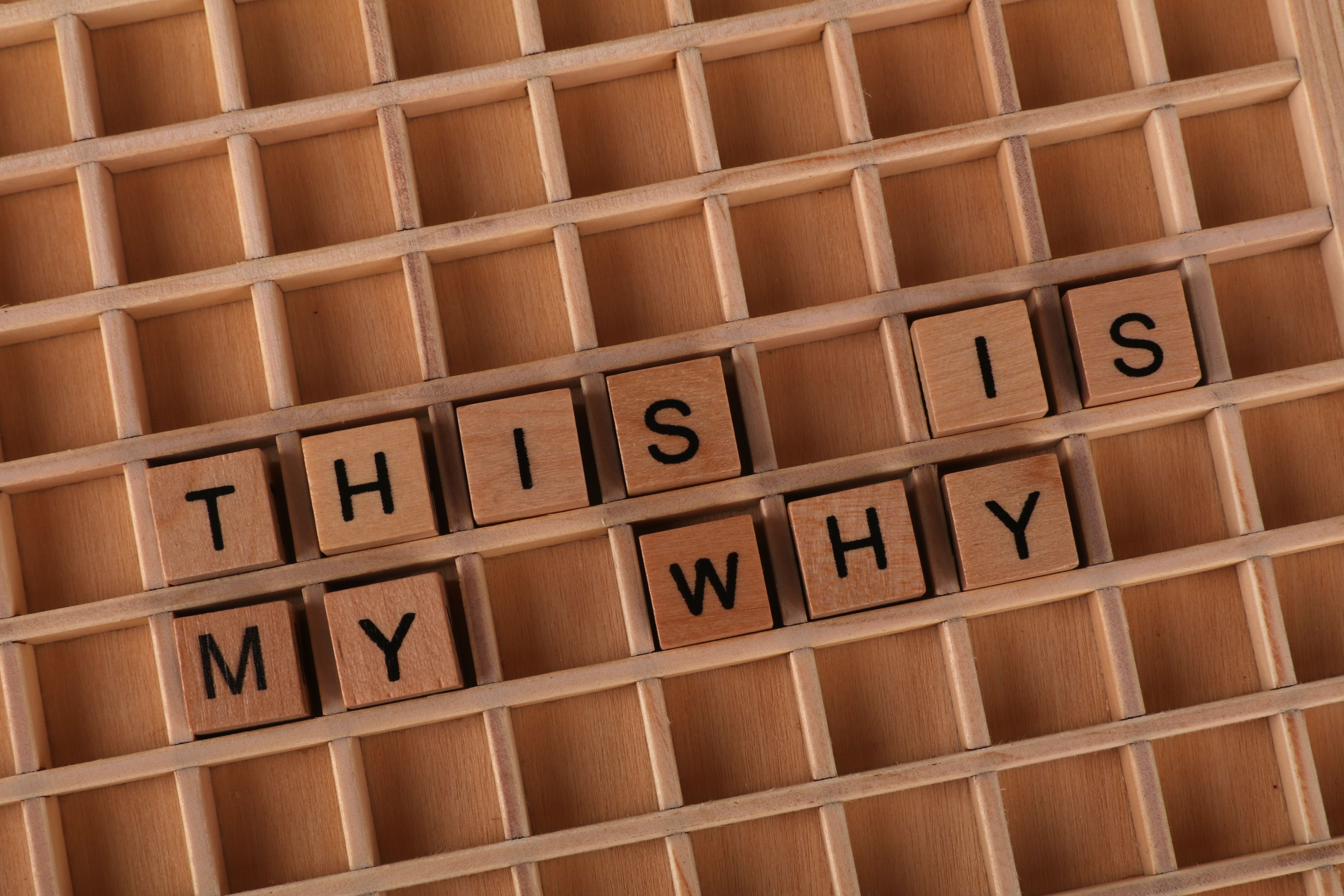 Wooden Scrabble tiles arranged to spell 'This is My Why' on a game board.