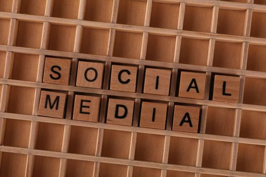 Close-up of wooden letter blocks spelling 'Social Media' on a wooden grid.