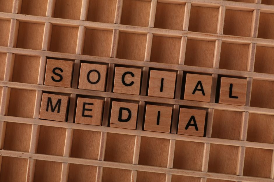 Close-up of wooden letter blocks spelling 'Social Media' on a wooden grid.