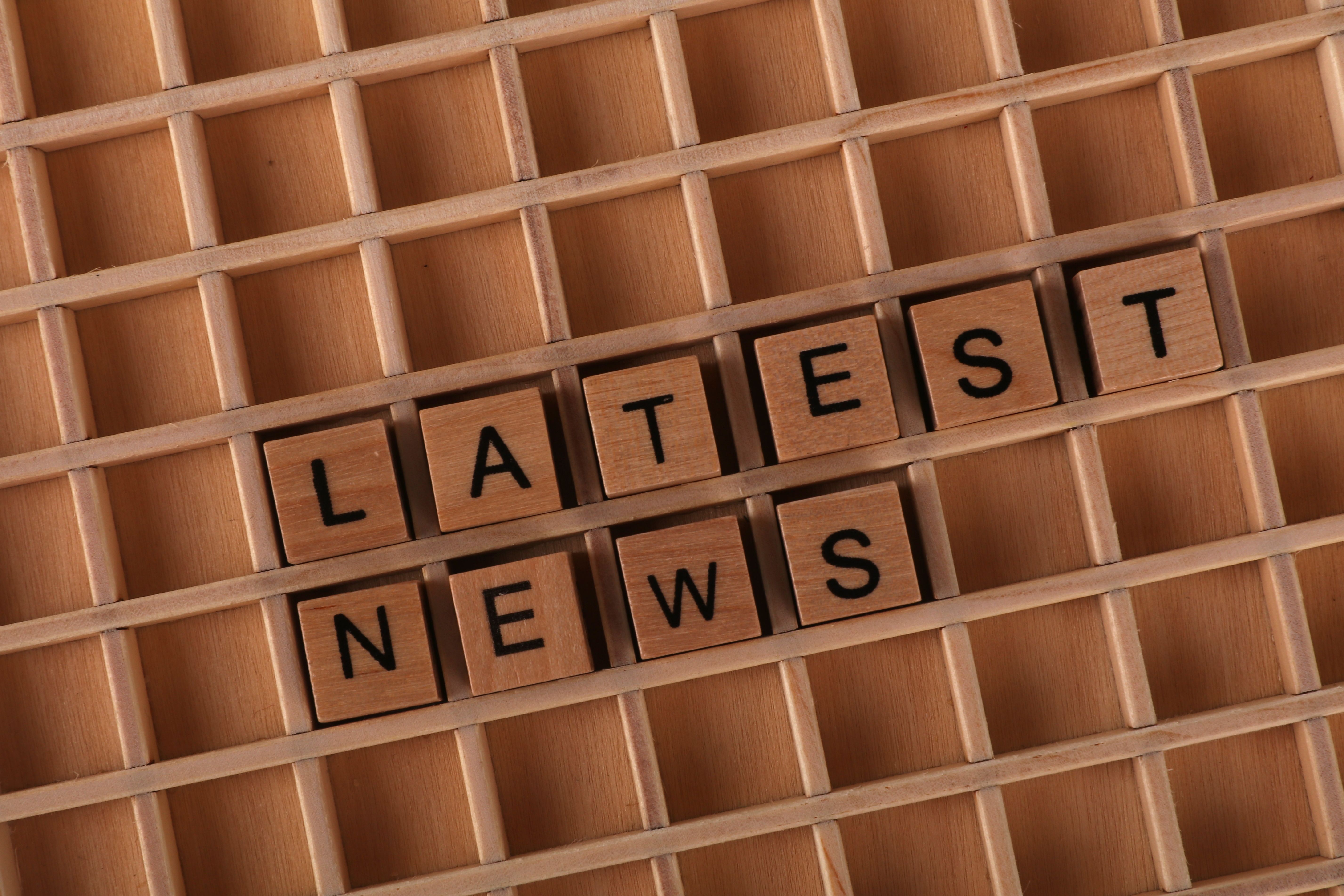 Wooden letter blocks spelling 'Latest News' on a grid surface. Ideal for media concepts.
