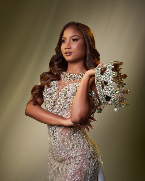 Free Portrait of a poised woman in a sparkling gown holding a majestic crown. Stock Photo
