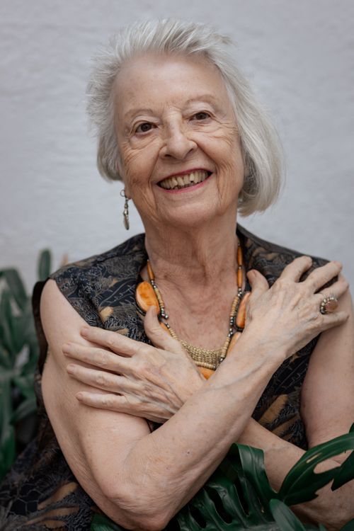 Free Senior woman smiling warmly, wearing jewelry, surrounded by greenery. Perfect for lifestyle and wellness themes. Stock Photo