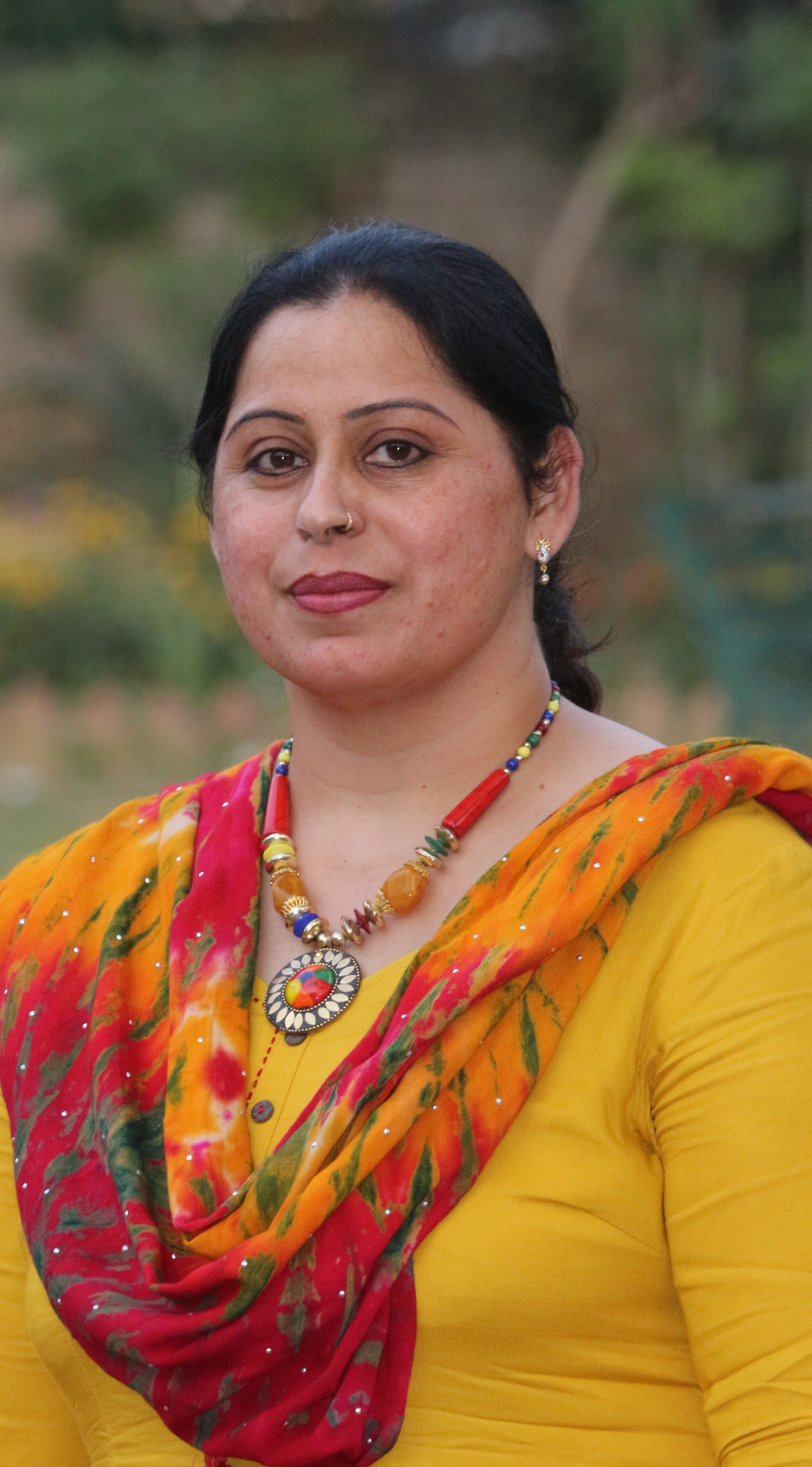 Close-up portrait of a woman wearing vibrant traditional clothing outdoors.