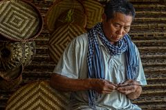 Elderly man skillfully weaving bamboo baskets, showcasing traditional craftsmanship.