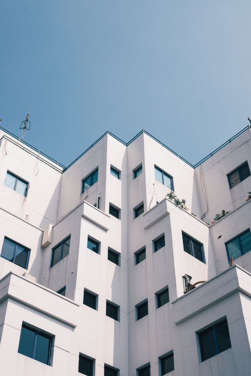 Free Low-angle view of a modern white building under a clear blue sky. Perfect for architecture or urban themes. Stock Photo