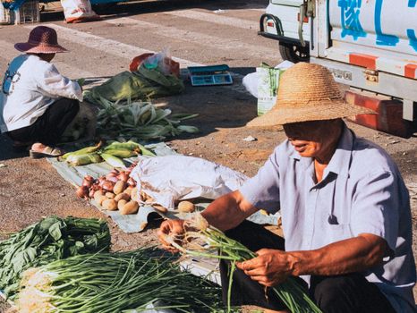 Farmers selling fresh vegetables at an outdoor market, showcasing rural life.
